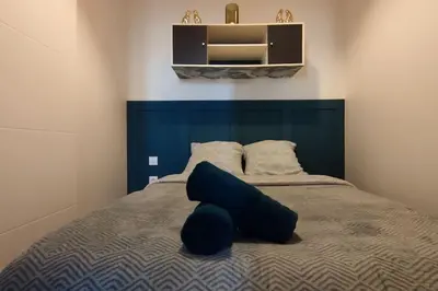 a bedroom with a bed with a blue headboard at T2 Cosy - Proche place Verdun in Castelnaudary