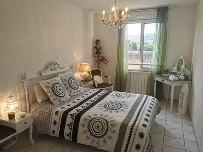 a bedroom with a bed and a window and a chandelier at Chambre avec vue panoramique sur la Cité Médiévale in Carcassonne