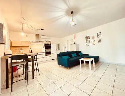 a living room with a blue couch and a kitchen at Maison avec piscine-climatisation-jardin in Ventenac en Minervois