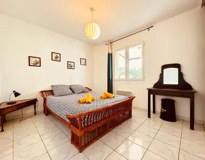 a bedroom with a bed and a table and a mirror at Maison avec piscine-climatisation-jardin in Ventenac en Minervois