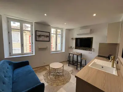 a living room with a blue couch and a kitchen at Le Merveilleux Voyage, Clim in Carcassonne