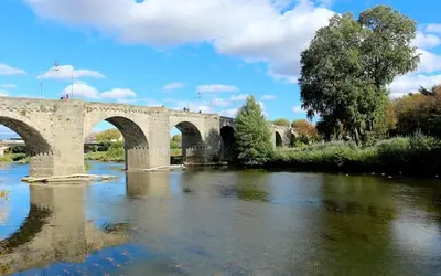 a stone bridge over a river with trees and water at Le Merveilleux Voyage, Clim in Carcassonne