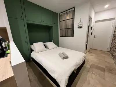 a bedroom with a large bed with a green cabinet at Le Gîte Médiéval - Clim - Lave Linge - Cité in Carcassonne