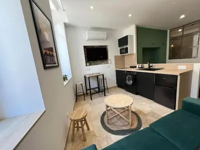 a living room and kitchen with a couch and a table at Le Gîte Médiéval - Clim - Lave Linge - Cité in Carcassonne