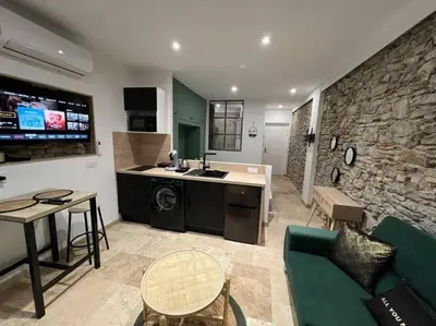 a kitchen and living room with a couch and a table at Le Gîte Médiéval - Clim - Lave Linge - Cité in Carcassonne