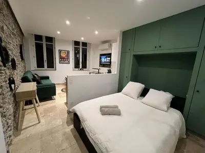 a bedroom with a large bed with a green headboard at Le Gîte Médiéval - Clim - Lave Linge - Cité in Carcassonne
