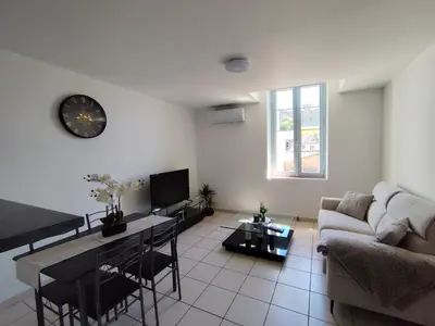 a living room with a couch and a clock on the wall at Appartement climatisé avec vue sur la cité in Carcassonne