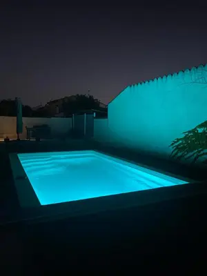 a swimming pool lit up at night with blue lights at Maison avec piscine et jardin in Salses-le-Chateau