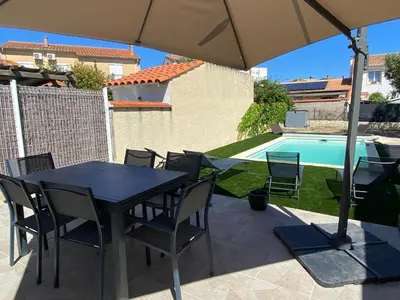a table and chairs with an umbrella next to a pool at Maison avec piscine et jardin in Salses-le-Chateau