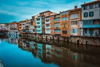 a row of colorful buildings next to a river at Gite Beau Soleil in Roquecourbe
