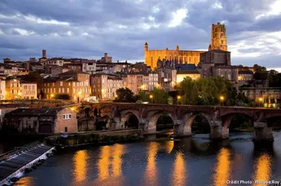 a bridge over a river with a city at night at Gite Beau Soleil in Roquecourbe