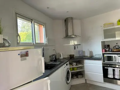a kitchen with white cabinets and a washer and dryer at Moderne Mini Maison - Quartier Résidentiel Calme in Lézignan-Corbières