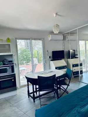 a living room with a table and chairs and a kitchen at Moderne Mini Maison - Quartier Résidentiel Calme in Lézignan-Corbières