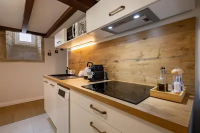 a kitchen with white cabinets and a wooden wall at Le Savane - Grand Triplex Confort & Chaleureux, 2 Salons in Castres