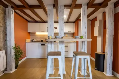 a kitchen with white counter stools and orange walls at Le Terracotta - Grand Triplex Confort & Chaleureux in Castres