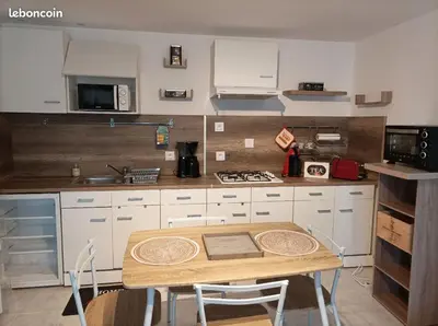 a kitchen with a wooden table and a kitchen with white cabinets at Chez Sabine La Campagne in Narbonne