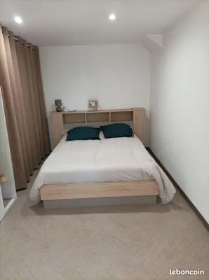 a bedroom with a wooden bed with two blue pillows at Chez Sabine La Campagne in Narbonne
