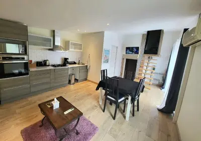 a living room with a table and a kitchen at Maisonnette indépendante 48m2 , parking privé, calme & confort in Lagarrigue