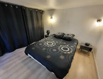 a bedroom with a bed with a black comforter at Maisonnette indépendante 48m2 , parking privé, calme & confort in Lagarrigue