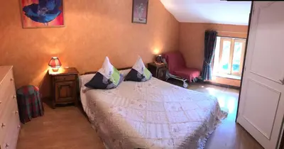 a bedroom with a bed and a red chair at Moulin de Record in Ferrières