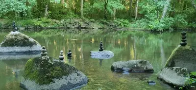 a group of rocks in a river with trees at Moulin de Record in Ferrières