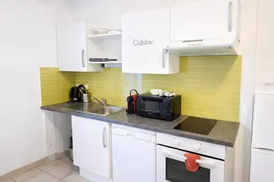 a kitchen with white cabinets and a sink and a microwave at Terrasse Privée - 4 Voyageurs - Proche Cité de Carcassonne in Carcassonne