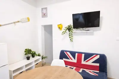 a living room with a table and a tv on a wall at Terrasse Privée - 4 Voyageurs - Proche Cité de Carcassonne in Carcassonne
