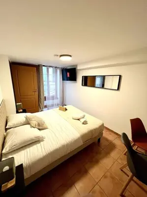 a bedroom with a large bed and a chair at Les chambres de la bastide - 203 in Carcassonne