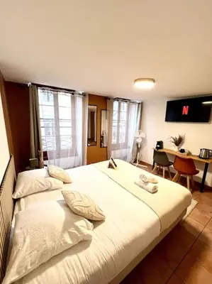 a hotel room with two beds and a desk and a desk at Les chambres de la bastide - 205 in Carcassonne