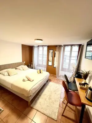 a bedroom with a large white bed and a desk at Les chambres de la bastide - 205 in Carcassonne