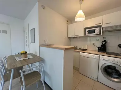 a kitchen with a table and a washing machine at T2 Calme et Paisible Parking Piscine in Carcassonne