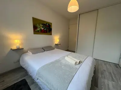 a bedroom with a white bed with two towels on it at T2 Calme et Paisible Parking Piscine in Carcassonne