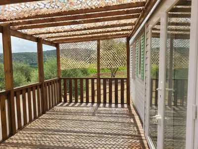 a screened porch with a pergola on a house at Camping Nysa Paziols in Paziols