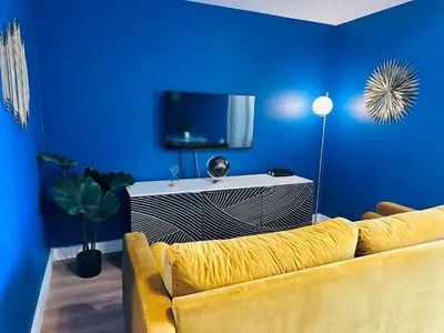 a living room with a yellow couch and a blue wall at You&Me hyper centre ville avec draps serviettes ménage final in Narbonne