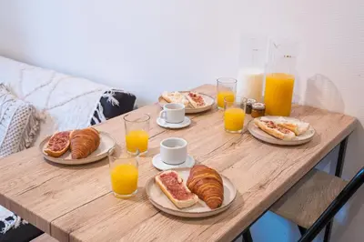 a wooden table with plates of pastries and orange juice at La Petite Bastide in Carcassonne