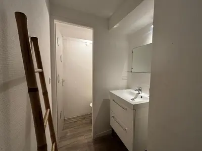 a white bathroom with a sink and a mirror at La Petite Bastide in Carcassonne