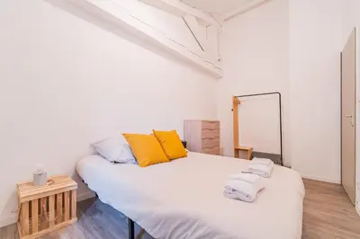 a bedroom with a large white bed with yellow pillows at La Petite Bastide in Carcassonne