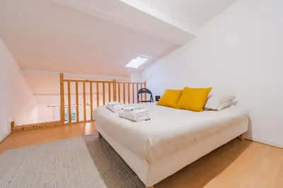 a bedroom with a bed with yellow pillows on it at La Petite Bastide in Carcassonne