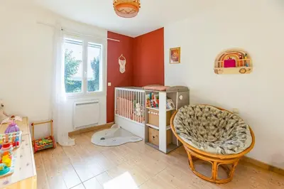 a baby room with a crib and a chair at Villa t4 à la campagne in Belleserre