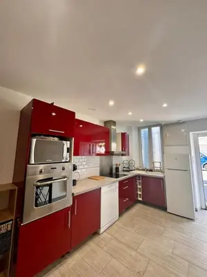 a kitchen with red cabinets and white appliances at La Maison de Sainte-Eulalie in Roubia