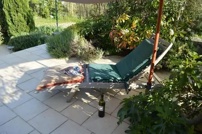 a chair sitting under an umbrella on a patio at Luxury cottage with Jacuzzi in Saint-Polycarpe in Saint-Polycarpe