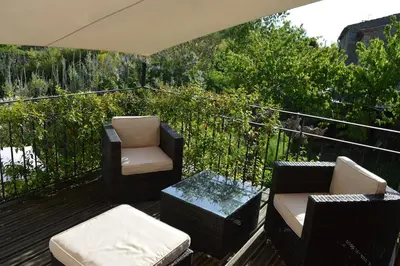 a balcony with chairs and a table and an umbrella at Luxury cottage with Jacuzzi in Saint-Polycarpe in Saint-Polycarpe