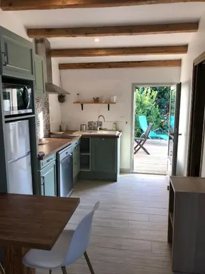 a kitchen with green cabinets and a table and a patio at Le Grenadier in Ventenac-Cabardès