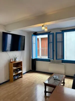 a living room with a flat screen tv and a table at Central apartment in Quillan in Quillan