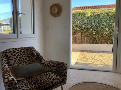 a leopard print chair sitting next to a sliding glass door at Ancienne maison de pêcheurs in Port-la-Nouvelle