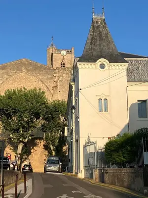 a building with a clock tower on top of a hill at Vignerone atypique proche du canal du midi à 30 min des plages in Capestang