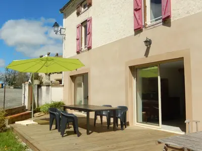 a patio with a table and chairs and a green umbrella at GITE Le calme de la campagne plus le confort in Viviès