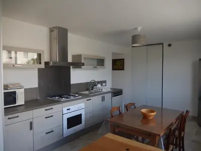 a kitchen with white cabinets and a wooden table at GITE Le calme de la campagne plus le confort in Viviès