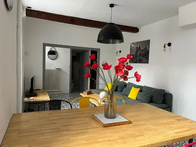 a vase of red flowers sitting on a wooden table at La maison du pont vieux - emplacement de parking gratuit - Proche Cité médiévale in Carcassonne