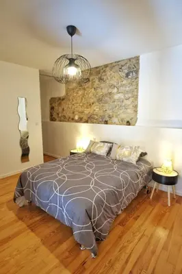 a bedroom with a bed and a stone wall at Loft de caractère centre-ville in Narbonne
